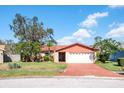 Inviting single-story home featuring a brick driveway and beautiful landscaping with mature trees at 7425 118Th Dr, Largo, FL 33773