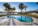 Backyard pool with view of the water, surrounded by a white fence, lush grass, and mature palm trees at 54 Central Ct, Tarpon Springs, FL 34689