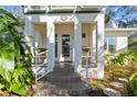 Inviting front porch featuring elegant pillars and a decorative entrance with lush surrounding greenery at 135 Aranda Ne St, St Petersburg, FL 33704