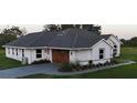A side view of the home showcases a woodgrain garage door, multiple windows, and professional landscaping at 7425 245Th E St, Myakka City, FL 34251