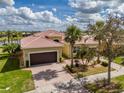 Aerial front view showcasing the house's tile roof, landscaping, and brick driveway at 16206 Diamond Bay Dr, Wimauma, FL 33598