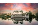 Lakewood National community entrance with lush palms and tranquil water reflections at sunset at 17520 Gawthrop Dr # 106, Lakewood Ranch, FL 34211