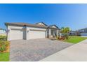 Beautiful one-story home with a three-car garage, brick-paved driveway, and a well-maintained lawn at 33277 Rosewood Bark Way, Wesley Chapel, FL 33545
