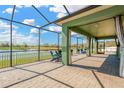 Screened patio with brick flooring, view of lake, and comfortable seating provides ideal outdoor relaxation at 13911 Artesa Bell Dr, Riverview, FL 33579