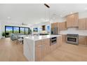 Bright, open kitchen with stainless steel appliances, wood cabinets, and a large island with a waterfall countertop at 1 Aqua Reserve Blvd, New Port Richey, FL 34652