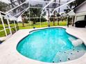 Bright screened-in pool features a jacuzzi, white tile surround, and view of the lush backyard with mature trees at 16311 Colwood Dr, Odessa, FL 33556