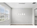 An empty dining room features hanging lights, a window, and views to the kitchen at 32346 Sapna Chime Dr, Wesley Chapel, FL 33545