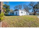 Angle view of a white single-story home with gray accents, and healthy green lawn at 3401 E Hanna Ave, Tampa, FL 33610
