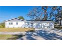 Single-story home with white paint, gray accents, a two-car garage, and a healthy front lawn at 3401 E Hanna Ave, Tampa, FL 33610