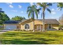 Charming single-story home featuring a well-manicured lawn, palm trees, and an attached two-car garage at 7213 Jones Rd, Odessa, FL 33556