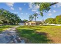Inviting home with a spacious front yard, bordered by a gravel driveway and mature trees, perfect for outdoor enjoyment at 7213 Jones Rd, Odessa, FL 33556