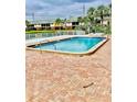 Community pool surrounded by a brick patio and fence with lush landscaping and condo buildings visible in the background at 200 Country Club Dr # 407, Largo, FL 33771