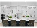 Modern white kitchen with chevron backsplash, stainless appliances, a large island and pendant lighting at 4406 W Euclid Ave, Tampa, FL 33629