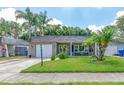 Charming single-story home with a well-manicured lawn, palm trees, and inviting front porch at 12261 Eldon Dr, Largo, FL 33774