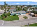 Aerial view of the charming coastal community with blue single story home, mature landscaping, and a private screened-in pool at 2103 W Vina Del Mar Blvd, St Pete Beach, FL 33706