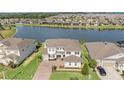 A stunning aerial view of the white home surrounded by a pristine lake and lush green landscape at 7721 Roma Dune Dr, Wesley Chapel, FL 33545