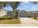 A single-story home with a two car garage, complemented by a well-maintained lawn and driveway at 18605 Le Dauphine Pl, Lutz, FL 33558