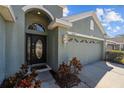 Front entrance with a decorative door and a two car garage with decorative windows at 18605 Le Dauphine Pl, Lutz, FL 33558