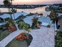 Aerial view of a beautiful waterfront home with a brick driveway and lush tropical landscaping, offering stunning water views at 6446 Lake Sunrise Dr, Apollo Beach, FL 33572
