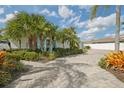 A beautiful exterior view of a waterfront property featuring lush landscaping and a well-maintained brick driveway at 6446 Lake Sunrise Dr, Apollo Beach, FL 33572