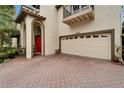 Exterior shot highlighting a two-car garage, red front door, arched entryway, and brick paver driveway at 10608 Hatteras Dr, Tampa, FL 33615