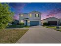 Charming two-story home with blue garage door, well-lit exterior, manicured lawn at twilight at 11827 Cara Field Ave, Riverview, FL 33579