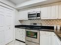 Kitchen featuring stainless steel appliances, white cabinets, and a modern backsplash for a sleek and functional space at 2606 Oak Cir, Tarpon Springs, FL 34689