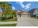Charming tan two-story home featuring an attached three-car garage and manicured front yard with mature palm trees at 7634 Nottinghill Sky Dr, Apollo Beach, FL 33572