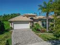 Attractive one-story home featuring a tile roof, brick driveway and manicured garden at 16135 Cape Coral Dr, Wimauma, FL 33598