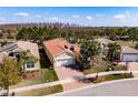 An aerial view of this beautiful house, with lush green surroundings, a brick driveway, and a barrel tile roof at 4822 Grand Banks Dr, Wimauma, FL 33598
