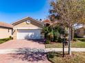 Charming single Gathering home featuring a two car garage, a brick driveway and mature landscaping at 4822 Grand Banks Dr, Wimauma, FL 33598