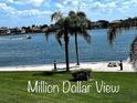 Breathtaking waterfront views from a lush green lawn with palm trees, beach, and boat in the distance at 5108 Brittany S Dr # 204, St Petersburg, FL 33715