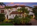 Mediterranean-style home with a red tile roof, tropical plants, and a private gated entrance at 705 Riviera Dunes Way, Palmetto, FL 34221