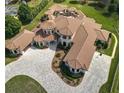 Sprawling luxury home featuring a terracotta roof, circular driveway, and meticulous landscaping at 11158 Warm Wind Way, Weeki Wachee, FL 34613