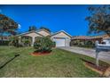 Single-Gathering home featuring a large front yard with manicured lawn, complemented by vibrant landscaping at 11427 Turtle Dove Pl, New Port Richey, FL 34654
