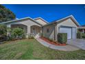 Single-Gathering home featuring a manicured lawn, vibrant landscaping, and a welcoming front porch at 11427 Turtle Dove Pl, New Port Richey, FL 34654