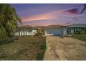 Inviting single-story home with a two-car garage, complemented by lush landscaping and a colorful sunset backdrop at 13614 Evelane Dr, Hudson, FL 34667