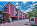 Exterior view of pink townhomes showing distinct architecture, private drive, and lush landscaping at 3390 W Maritana Dr # 4, St Pete Beach, FL 33706