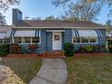 Charming single-story home with blue siding, awnings, a chimney, and a landscaped front yard at 1213 60Th S St, Gulfport, FL 33707