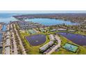 Expansive aerial view showcasing a waterfront community with tennis courts and a beautiful pond at 4744 Snook Se Dr, St Petersburg, FL 33705