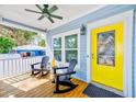 Cozy front porch with seating, ceiling fan, yellow door, and charming details creating a welcoming entrance at 112 17Th E St, Bradenton, FL 34208