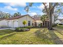 Inviting home exterior with manicured lawn, complemented by palm trees, flower beds and a two-car garage at 14766 Feather Cove Ln, Clearwater, FL 33762