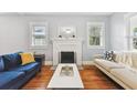 Bright living room featuring a decorative fireplace, hardwood floors, and windows that provide ample natural light at 104 W Henry Ave, Tampa, FL 33604