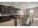 Charming kitchen featuring dark wood cabinets, a large island with seating, and modern stainless steel appliances at 11717 Navajo Sandstone St, Riverview, FL 33579