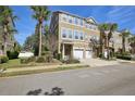 Tan townhome with a two-car garage, mature palm trees, and manicured lawn at 2967 Bayshore Pointe Dr, Tampa, FL 33611