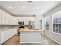 Bright kitchen with white cabinets, center island, stainless appliances, and stylish backsplash at 2967 Bayshore Pointe Dr, Tampa, FL 33611