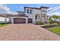 Charming Mediterranean-style home with paved driveway and a spacious three-car garage at 912 Symphony Beach Ln, Apollo Beach, FL 33572