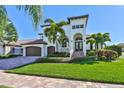Elegant two-story home with lush landscaping, arched entryway, and spacious three-car garage at 912 Symphony Beach Ln, Apollo Beach, FL 33572