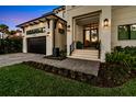 Modern home with brick driveway, two-car garage, manicured lawn, and well lit entry way at 5004 S The Riviera, Tampa, FL 33609