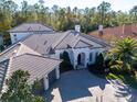 Aerial view of a house with brick driveway, lush lawn, pristine landscaping and a barrel tile roof at 2607 Hawks Landing Blvd, Palm Harbor, FL 34685